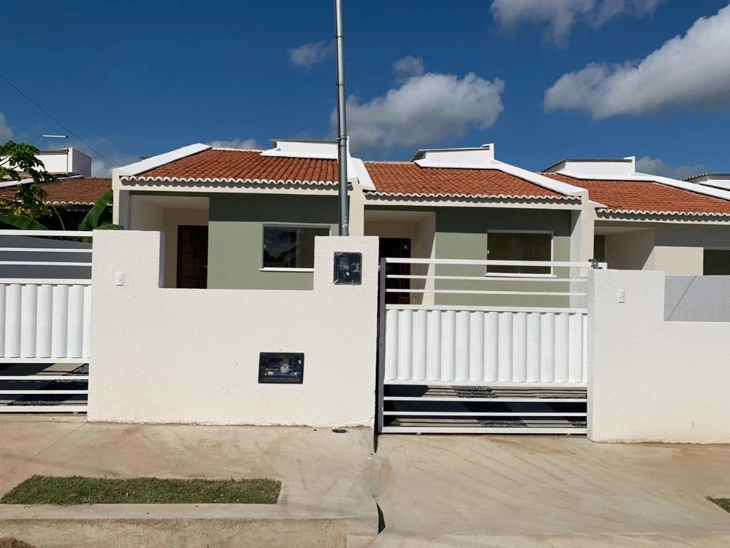 Fachadas de residências térreas com telhado cerâmico, portões brancos e detalhes em verde